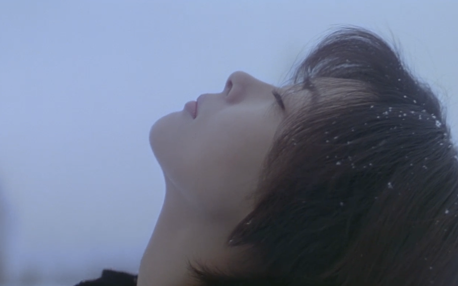 A woman looks up at the sky with her eyes closed in the movie “Love Letter”.